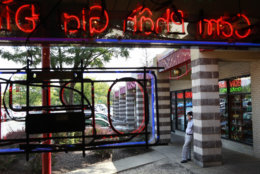 Seen through the window of Tay Do, a Vietnamese restaurant, a man smokes outside at the Eden Center in Falls Church, Va. on Thursday, Aug. 26, 2010. Virginia's new smoking laws have made it illegal to smoke inside restaurants and bars. (AP Photo/Jacquelyn Martin)