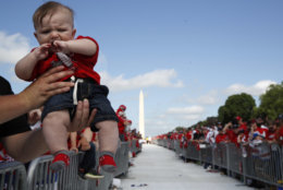 Four-month-old hockey fan C.J. Ford, of Elliott City, Md., is held up by his father as fans line the National Mall ahead of a victory parade and rally for the Washington Capitals in celebration of winning the Stanley Cup, Tuesday, June 12, 2018, in Washington. The baby has already been to eleven games as his parents are season ticket holders. (AP Photo/Jacquelyn Martin)