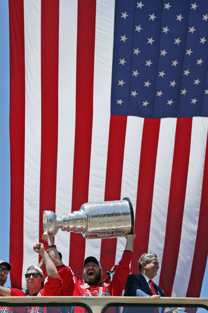 Washington Capitals left wing Alex Ovechkin (8), from Russia, holds up the Stanley Cup, with center Nicklas Backstrom (19), from Sweden, left, and owner Ted Leonsis, right, during a victory parade, Tuesday, June 12, 2018, in Washington. (AP Photo/Alex Brandon, Pool)