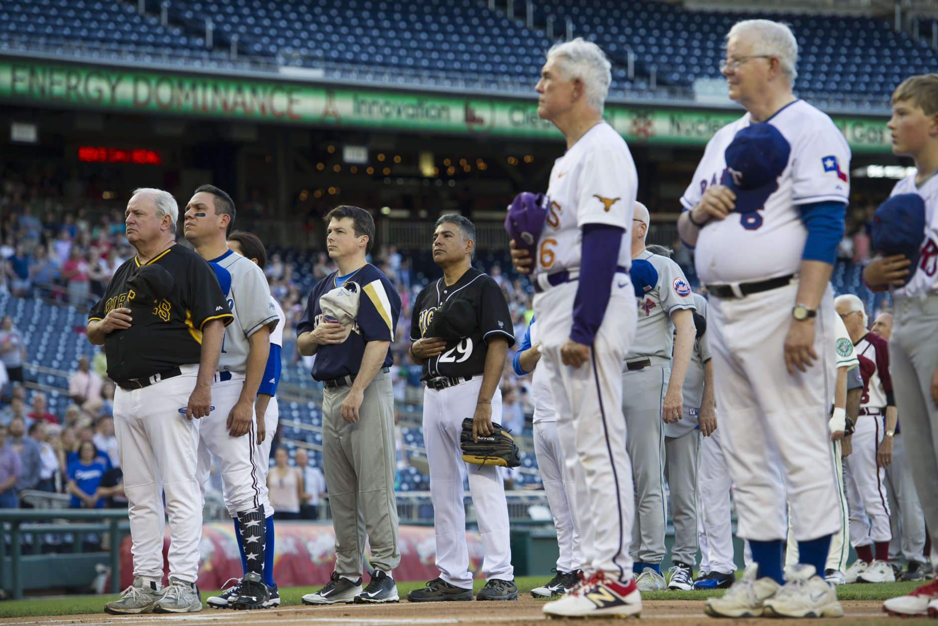 Members of the Democratic and Republican baseball teams stand for the national anthem to start the 57th Congressional Baseball Game at National's Park in Washington, Thursday, June 14, 2018. On June 14, 2017, some Congressional members were victims of a shooting at the baseball field they were practicing on in Alexandria, Va. (AP Photo/Cliff Owen)