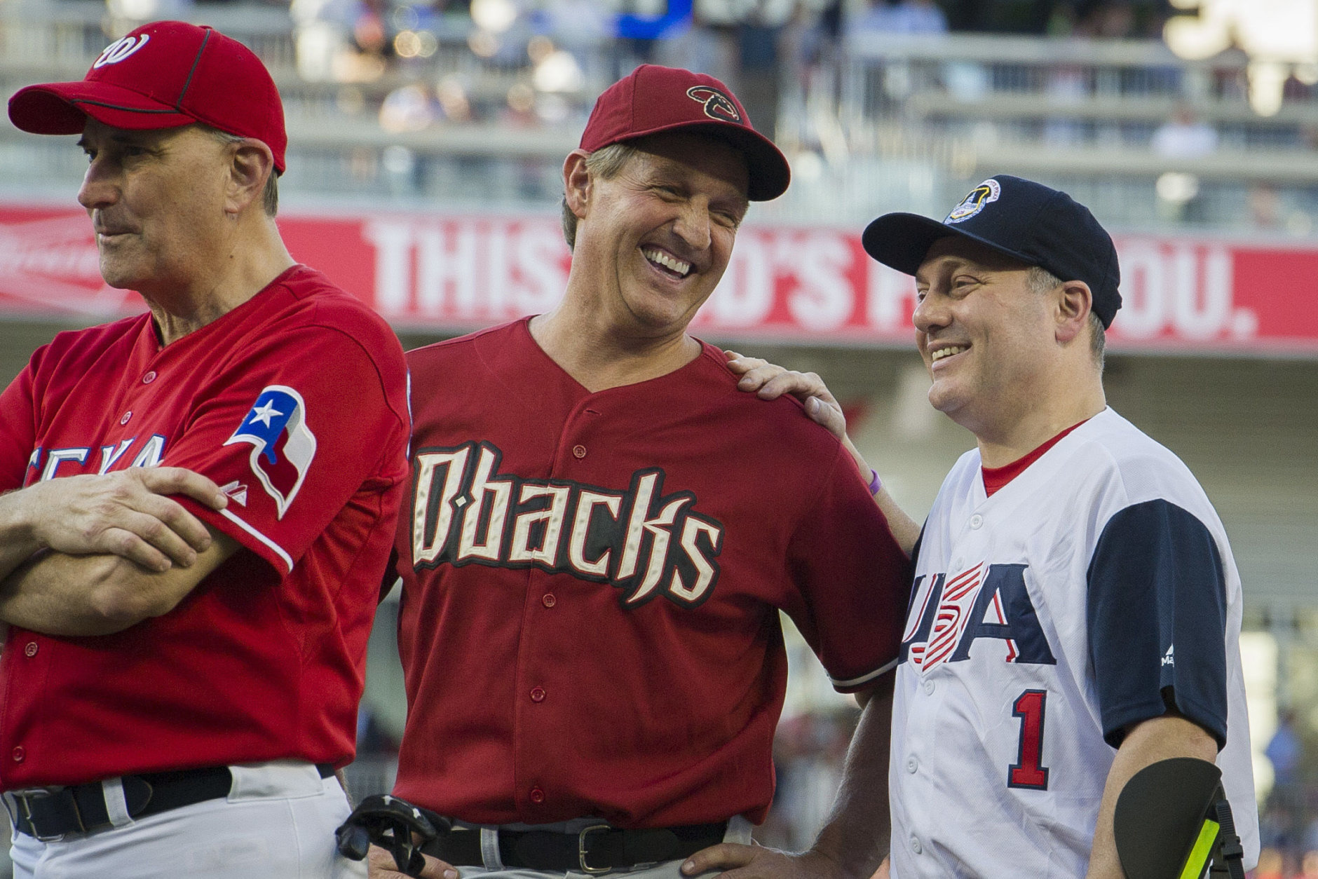 Rep. Jeff Flake, R-Ariz., center, talks with Rep. Steve Scalise, R- La., at the start of the 57th Congressional Baseball Game at National's Park in Washington, Thursday, June 14, 2018. Scalise, the House majority whip who was shot at a Republican baseball practice a year ago, fielded a ground ball and threw out the first batter of the annual congressional baseball game Thursday. (AP Photo/Cliff Owen)
