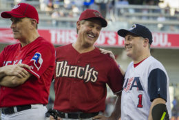 Rep. Jeff Flake, R-Ariz., center, talks with Rep. Steve Scalise, R- La., at the start of the 57th Congressional Baseball Game at National's Park in Washington, Thursday, June 14, 2018. Scalise, the House majority whip who was shot at a Republican baseball practice a year ago, fielded a ground ball and threw out the first batter of the annual congressional baseball game Thursday. (AP Photo/Cliff Owen)
