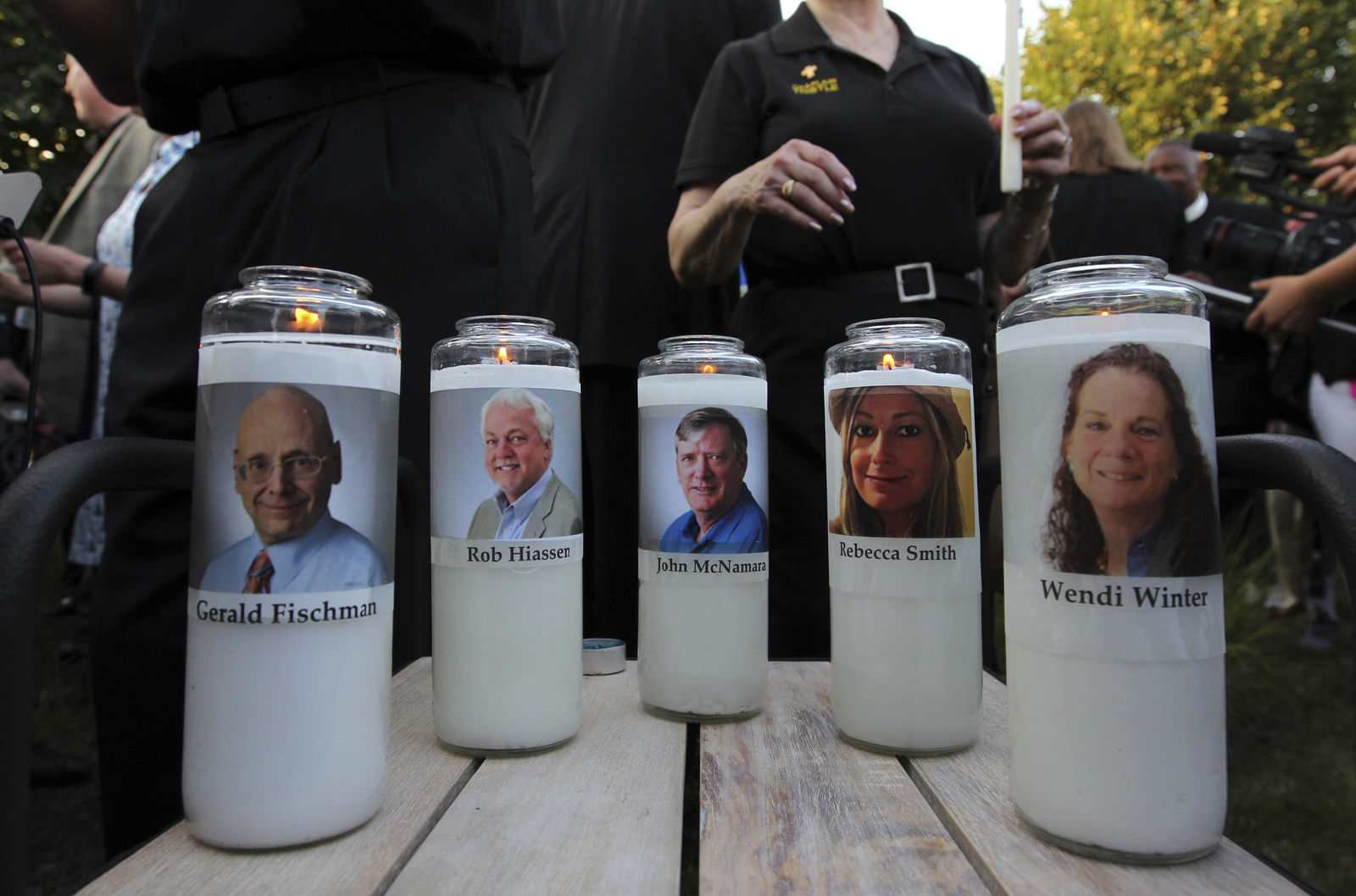 Photos of five journalists adorn candles during a vigil across the street from where they  were slain in their newsroom in Annapolis, Md., Friday, June 29, 2018. Prosecutors say Jarrod W. Ramos opened fire Thursday in the Capital Gazette newsroom. (AP Photo/Jose Luis Magana)