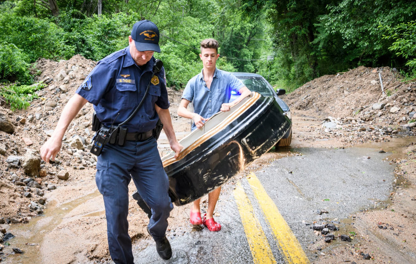 A Howard County officer helps Mark Haver carry the Ellicott City clock, which was swept away during Sunday's flood. (Courtesy Howard County Government)