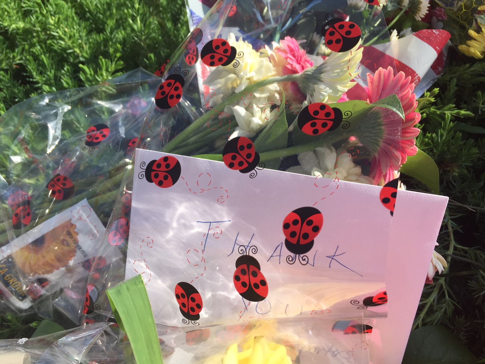 A bouquet of flowers and a card are seen at a memorial for the five victims of a shooting at the Capital Gazette in Annapolis. (WTOP/John Domen) 