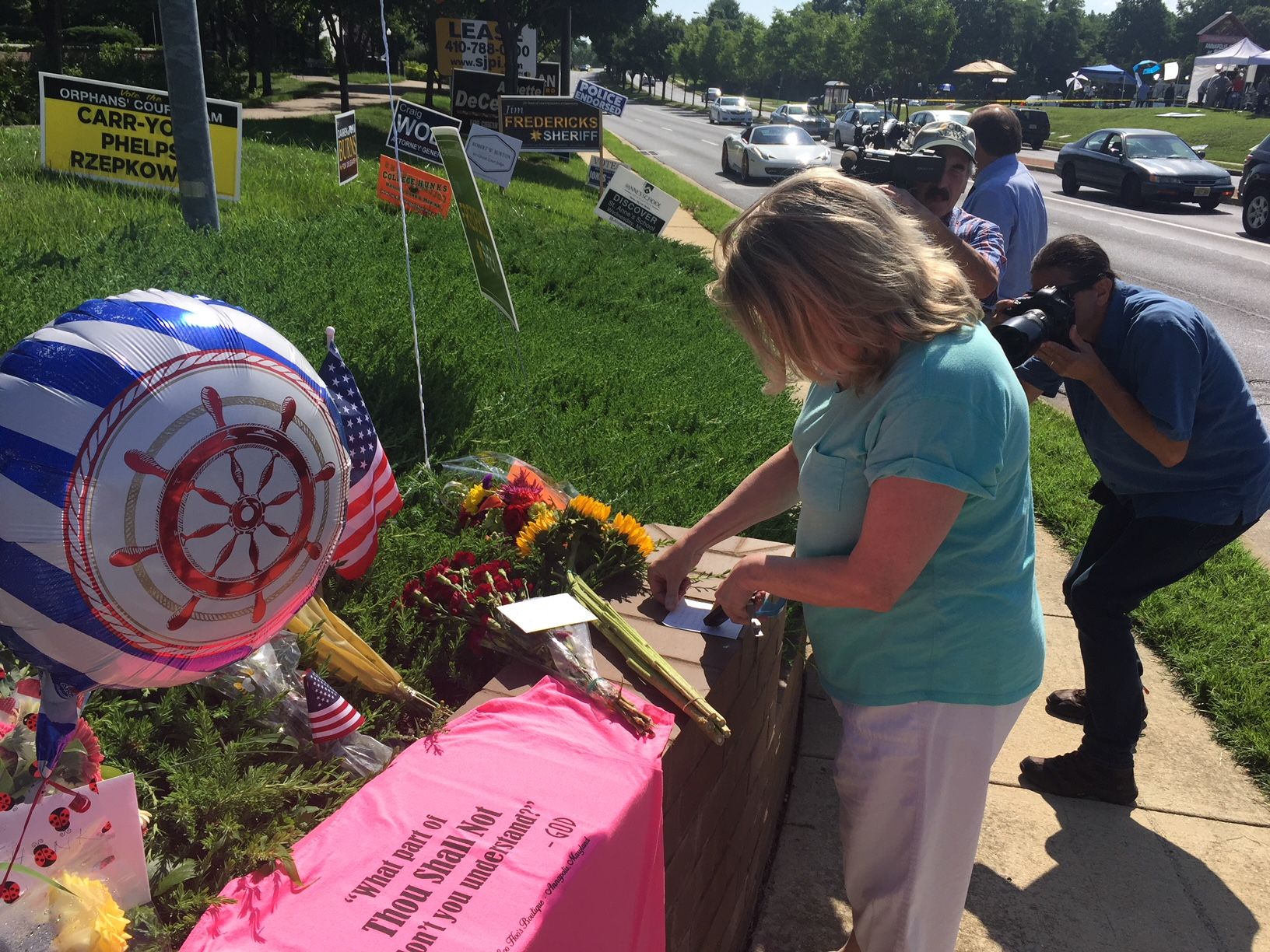 A woman is seen placing a note at a memorial in Annapolis for the victims of the shooting at the Capital Gazette newspaper. (WTOP/John Domen) 