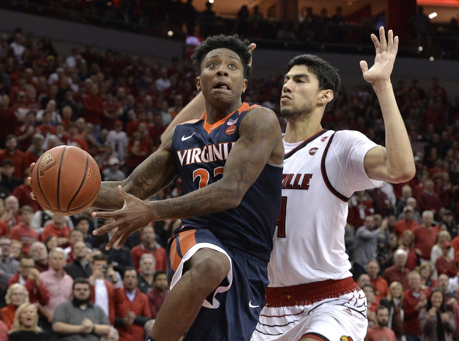 Virginia guard Nigel Johnson (23) goes in for a layup past the defense of Louisville forward Anas Mahmoud (14) during the first half of an NCAA college basketball game, Thursday, March 1, 2018, in Louisville, Ky. (AP Photo/Timothy D. Easley)