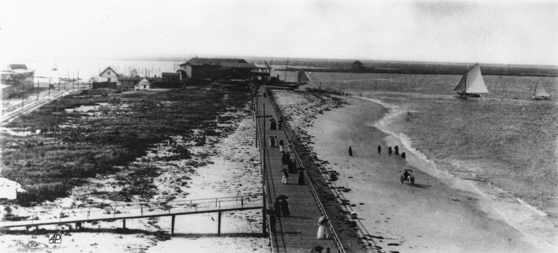 People strolling the boardwalk in Atlantic City, N.J., carry black umbrellas to ward off the sun, as horse drawn buggies wheel up and down the sandy beaches and picturesque sailboats float on the horizon, in 1895. Exact date is unknown. (AP Photo)