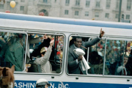 Washington Redskins defensive end Dexter Manley holds the championship trophy in his right hand as he leans out a bus during a parade honoring the world professional football championship team in Washington, D.C., Feb. 3, 1988. The Redskins beat the Broncos by a score of 42-10 to win Super Bowl XXII. (AP Photo/Barry Thumma)