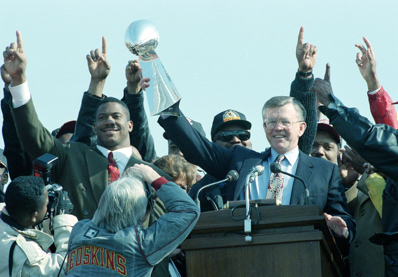Washington Redskins coach Joe Gibbs, surrounded by his players, holds the Vince Lombardi trophy during a rally for the Super Bowl champions on the Mall in Washington, D.C., Jan. 28, 1992. The Redskins defeated the Buffalo Bills in the Super Bowl XXVI game, 37-24. Redskins linebacker Ravin Caldwell is at left. (AP Photo/Doug Mills)