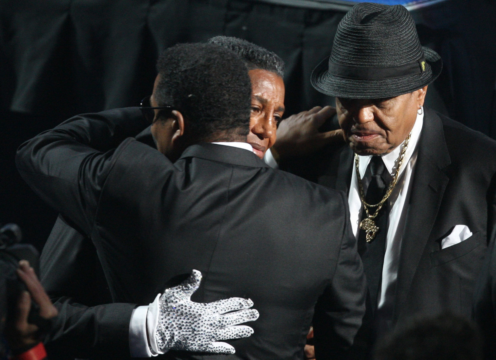 Brothers Jermaine, left, and Jackie, back to the camera, embrace as their father Joe Jackson, right, watches, during memorial services for Michael Jackson at the Staples Center in Los Angeles on Tuesday, July 7, 2009. (AP Photo/Mario Anzuoni, Pool)