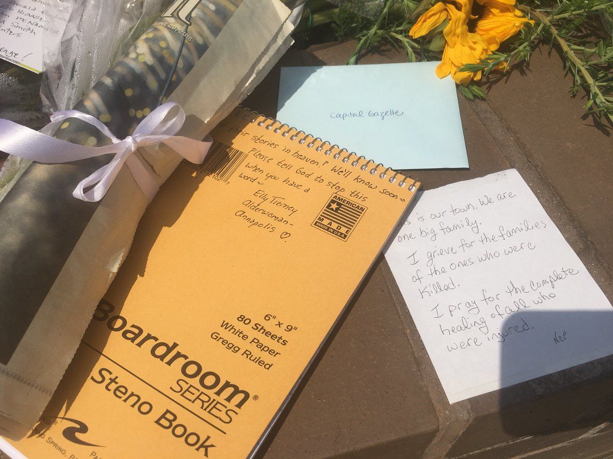 A press notebook, cards and gifts are seen at a memorial outside of the Capital Gazette where five people were killed by a gunman. (WTOP/Mike Murillo)