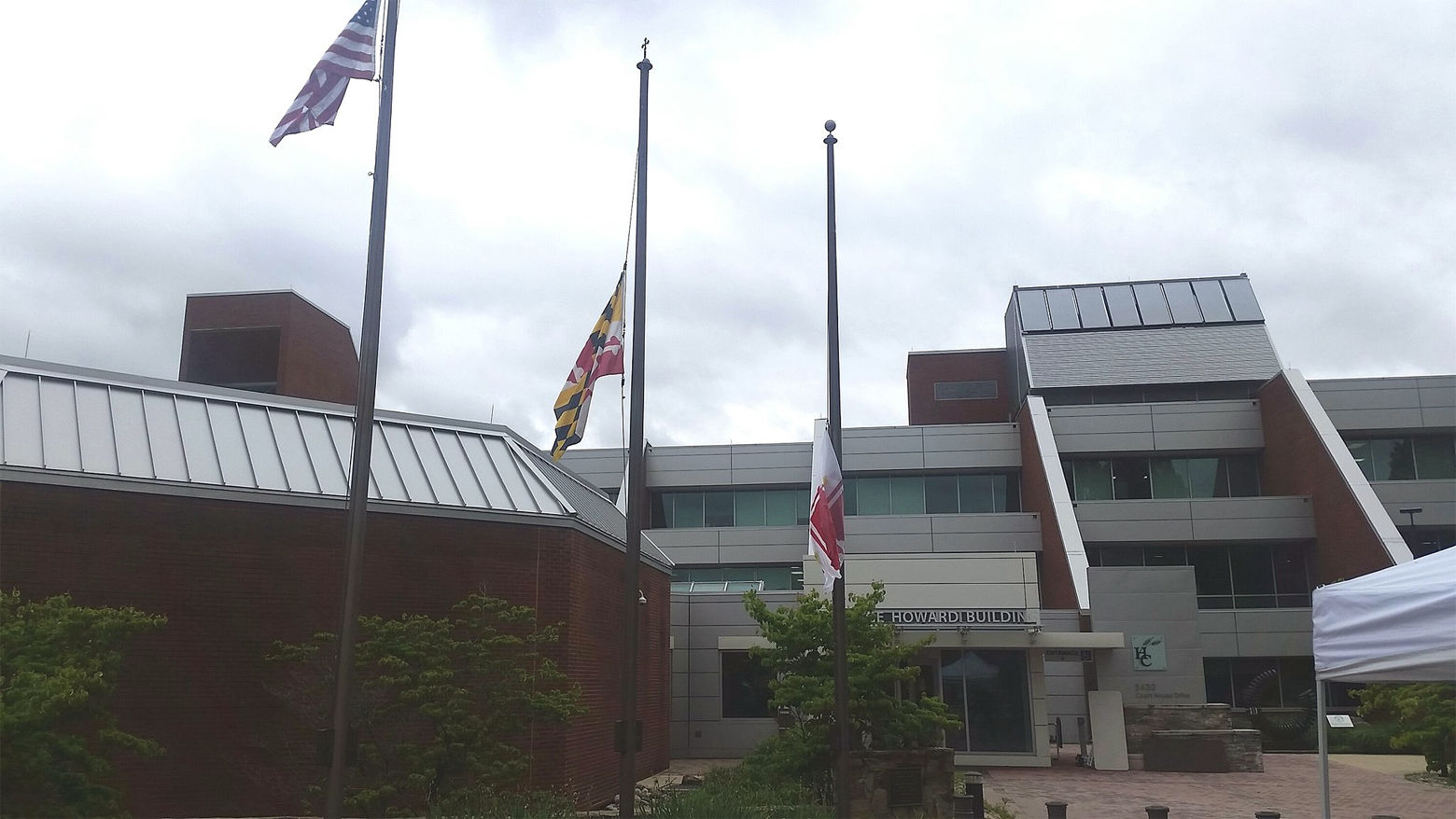 The state flag of Maryland and the flag of Howard County fly at half mast in honor of National Guardsman Eddison Hermon who was killed when floodwaters rushed through Ellicott City on May 27, 2018. (WTOP/Kathy Stewart)