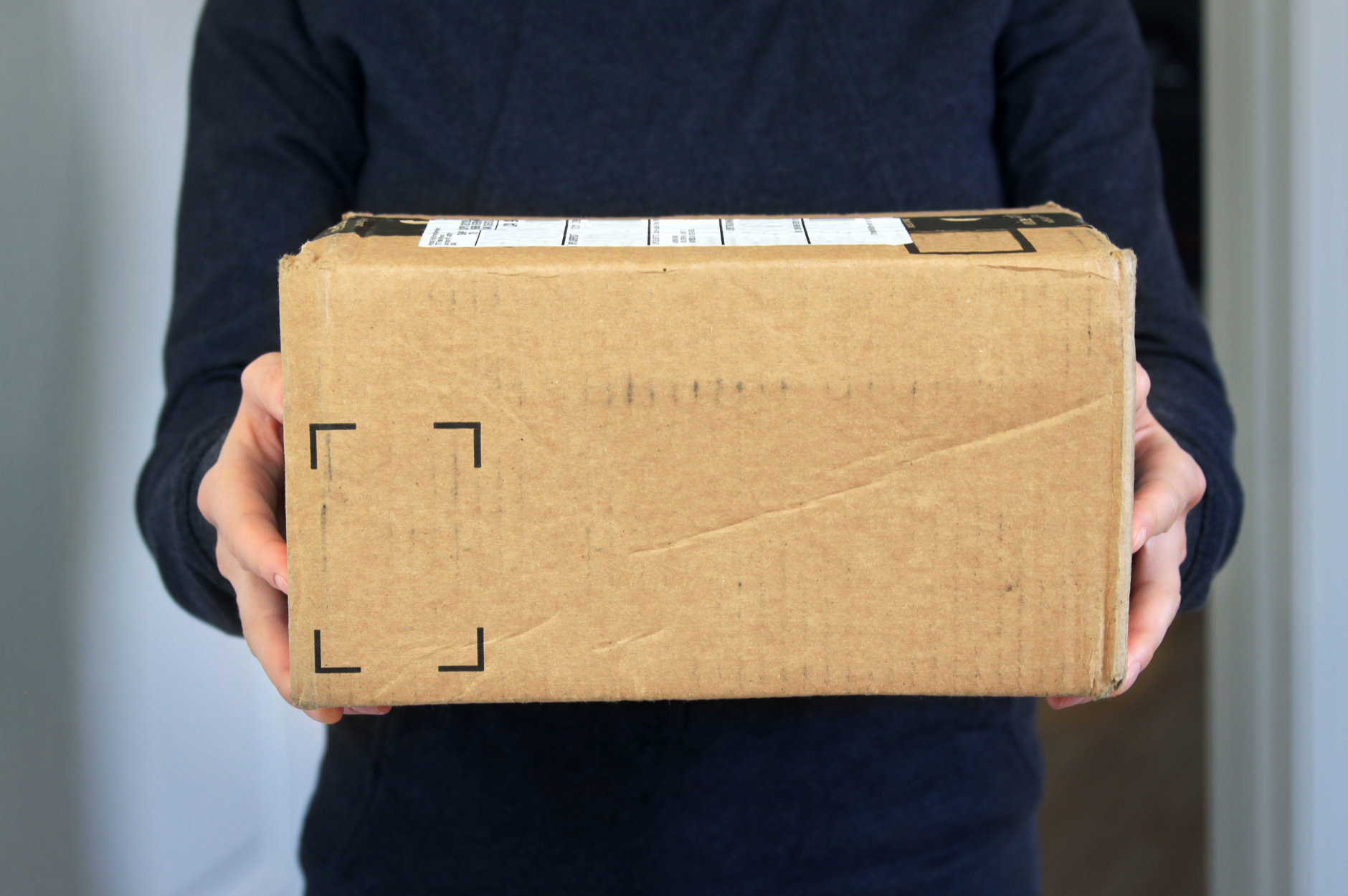 A woman holding cardboard box package delivered at home