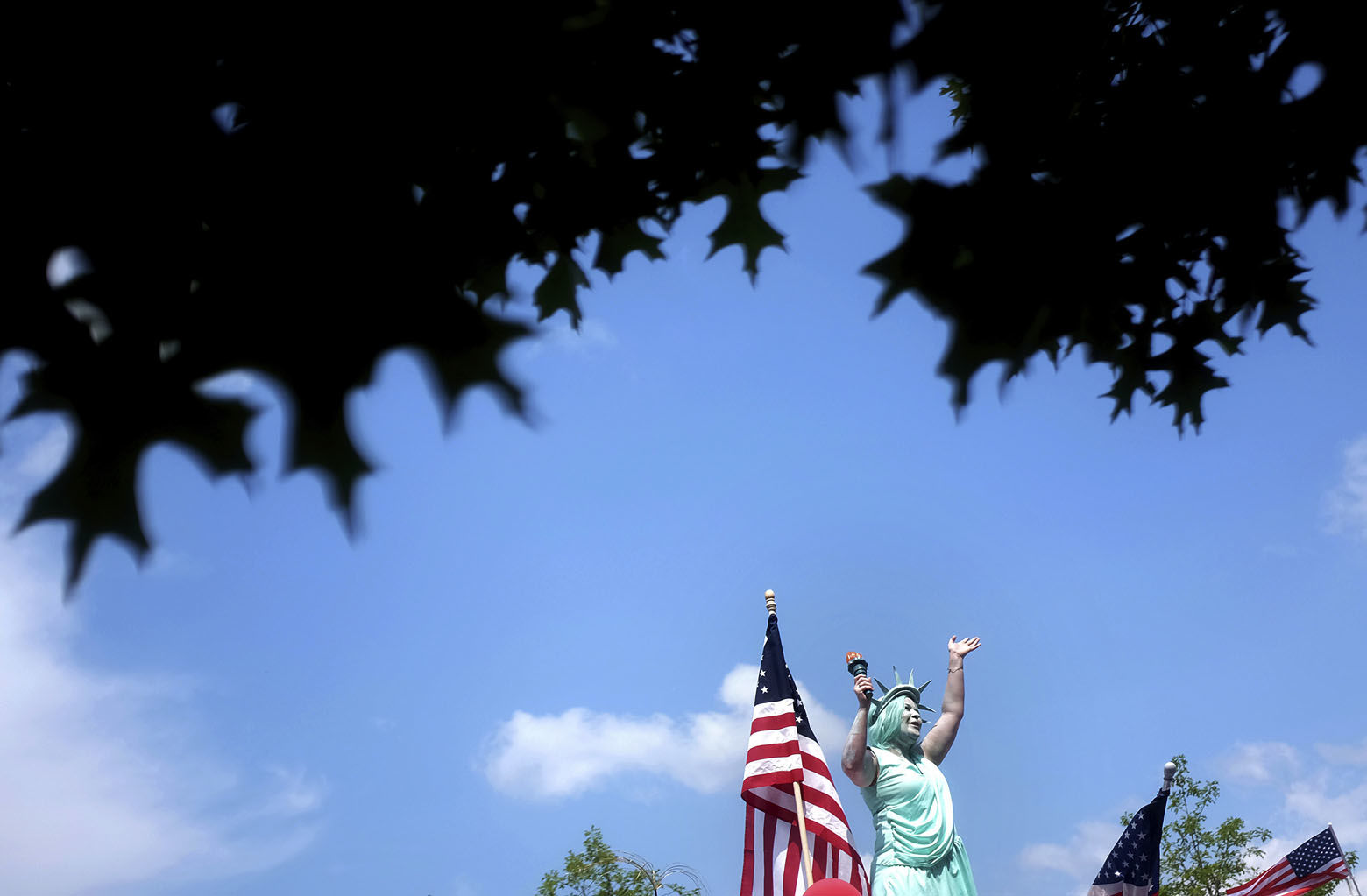 A woman dressed at the Statue of Liberty waves to the crowd while riding on a float in the Fourth of July parade in Marietta, Ga., Wednesday, July 4, 2018. (AP Photo/David Goldman)