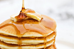 Maple syrup pouring onto pancakes. Shallow DOF with focus on syrup and butter.