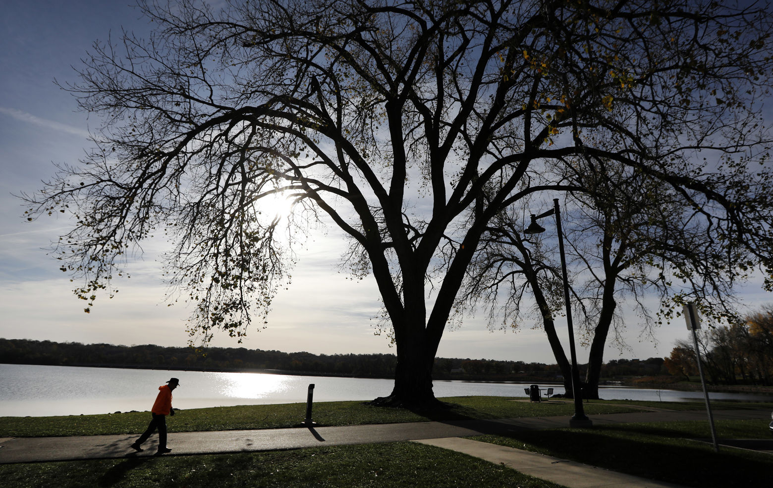 A man walks on the path around Gray's Lake Park, Tuesday, Oct. 31, 2017, in Des Moines, Iowa. (AP Photo/Charlie Neibergall)