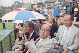 Baseball Commissioner Fay Vincent shares his umbrella with friends, Tuesday, July 10, 1990 as a light rain fell at Chicago's Wrigley Field threatening the start of the 61st annual All-Star Game. (AP Photo/John Swart)