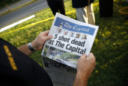 Steve Schuh, county executive of Anne Arundel County, holds a copy of The Capital Gazette near the scene of a shooting at the newspaper's office, Friday, June 29, 2018, in Annapolis, Md. (AP Photo/Patrick Semansky)