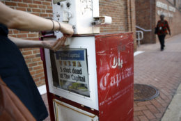 Angela Gentile, of College Park, Md., tries to buy a copy of The Capital Gazette from a newspaper rack, Friday, June 29, 2018, in Annapolis, Md. A man armed with smoke grenades and a shotgun attacked journalists in the newspaper's building Thursday, killing several people before police quickly stormed the building and arrested him, police and witnesses said. (AP Photo/Patrick Semansky)
