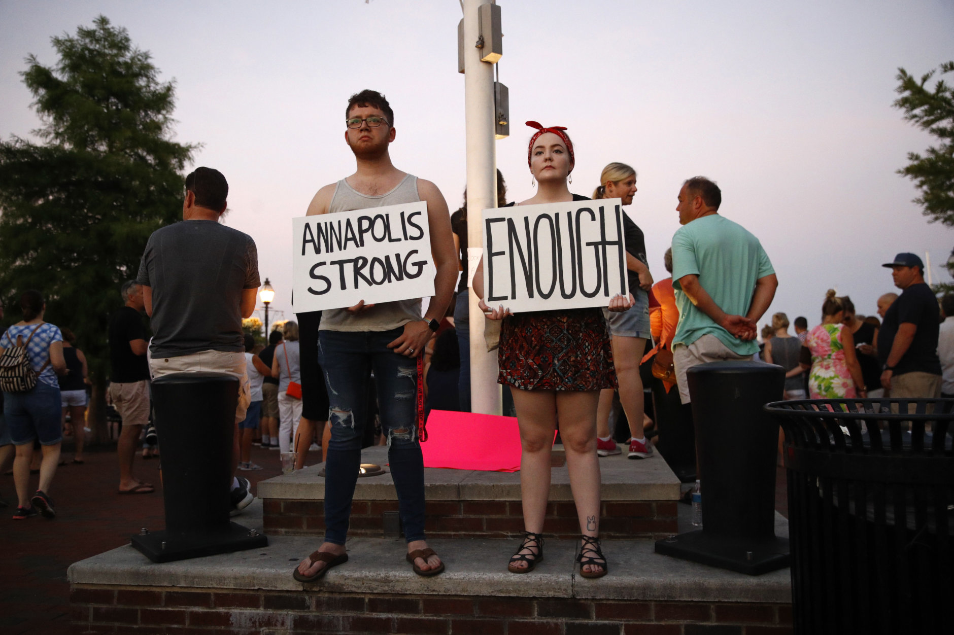 Tanner Piekarski, left, and Kylie Myles hold signs during a vigil in response to a shooting at The Capital Gazette newspaper office, Friday, June 29, 2018, in Annapolis, Md. Prosecutors say Jarrod W. Ramos opened fire Thursday in the Capital Gazette newsroom. (AP Photo/Patrick Semansky)