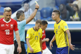 Referee Damir Skomina from Slovenia, second left, shows a yellow card to Sweden's Mikael Lustig during the round of 16 match between Switzerland and Sweden at the 2018 soccer World Cup in the St. Petersburg Stadium, in St. Petersburg, Russia, Tuesday, July 3, 2018. (AP Photo/Efrem Lukatsky)