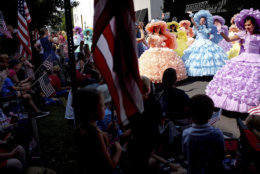 Southern belles wearing colorful antebellum dresses wave to the crowd while walking in the Fourth of July parade in Marietta, Ga., Wednesday, July 4, 2018. (AP Photo/David Goldman)
