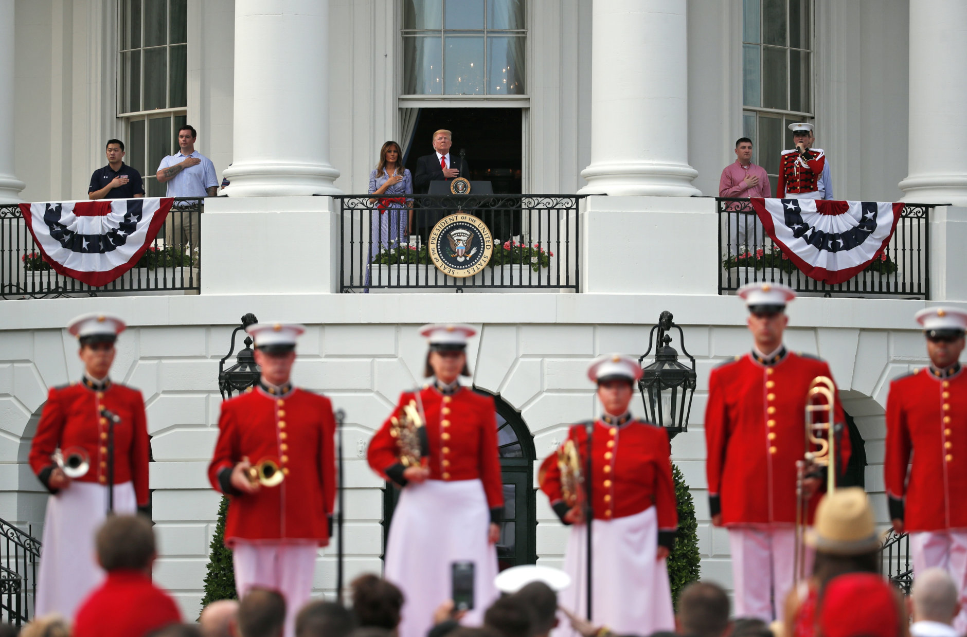 President Donald Trump, top center, accompanied by first lady Melania Trump, places his hand over his heart during the playing of the national anthem during an afternoon picnic for military families on the South Lawn of the White House, Wednesday, July 4, 2018, in Washington. (AP Photo/Alex Brandon)