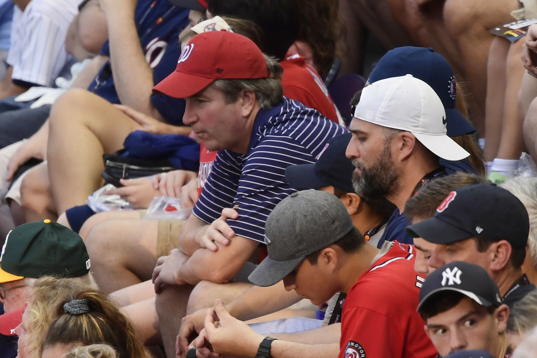 CORRECTS SPELLING TO KAVANAUGH, INSTEAD OF KAVANUAGH - Supreme Court nominee Judge Brett Kavanaugh, in red hat, sits in the stands before the Major League Baseball All-star Game, Tuesday, July 17, 2018 in Washington. (AP Photo/Susan Walsh)
