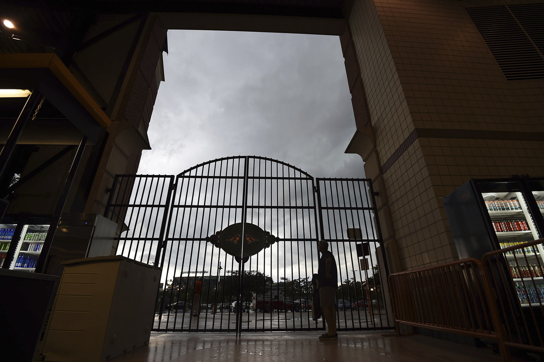 A fan stays dry as thunderstorms pass over Oriole Park at Camden Yards before a baseball game between the Baltimore Orioles and the Tampa Bay Rays on Friday, July 27, 2018, in Baltimore. (AP Photo/Gail Burton)