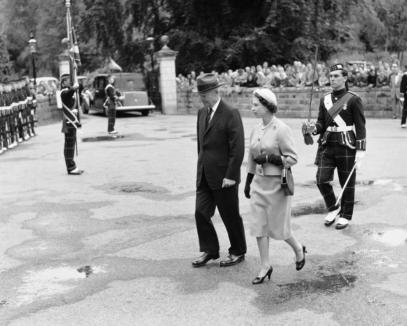 President Dwight D. Eisenhower walks through the grounds of Balmoral Castle in Scotland, Aug. 28, 1959 with Queen Elizabeth II after his arrival from London. They are followed by a soldier bearing the Queen's sword. (AP Photo)