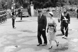 President Dwight D. Eisenhower walks through the grounds of Balmoral Castle in Scotland, Aug. 28, 1959 with Queen Elizabeth II after his arrival from London. They are followed by a soldier bearing the Queen's sword. (AP Photo)