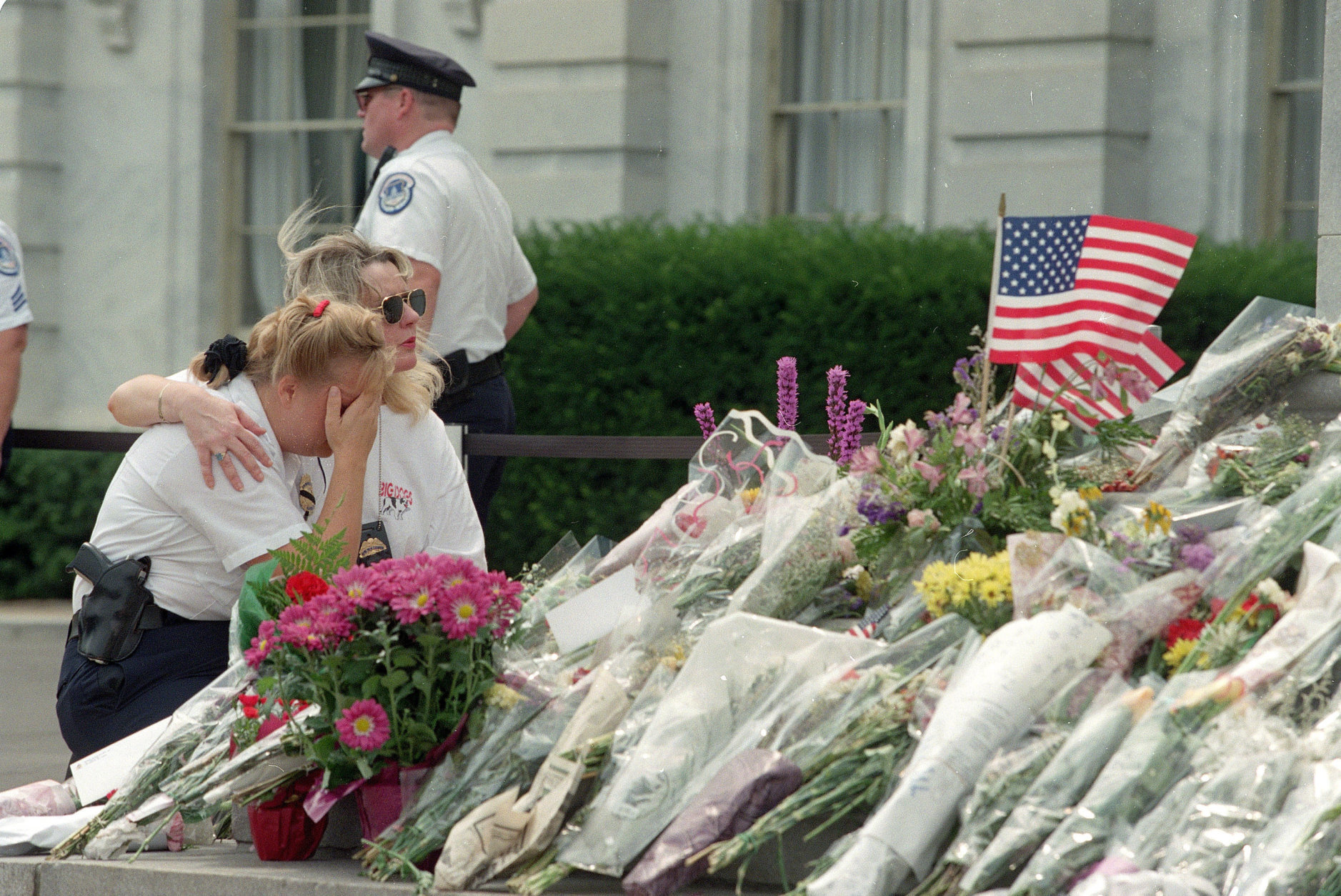 Capitol police officer Heidi Milhan, left, is comforted by an unidentified Capitol Hill visitor near flowers placed on the steps of the Capitol Monday, July 27,1998, in honor of two Capitol police officers who were shot and killed. (AP Photo/Khue Bui)