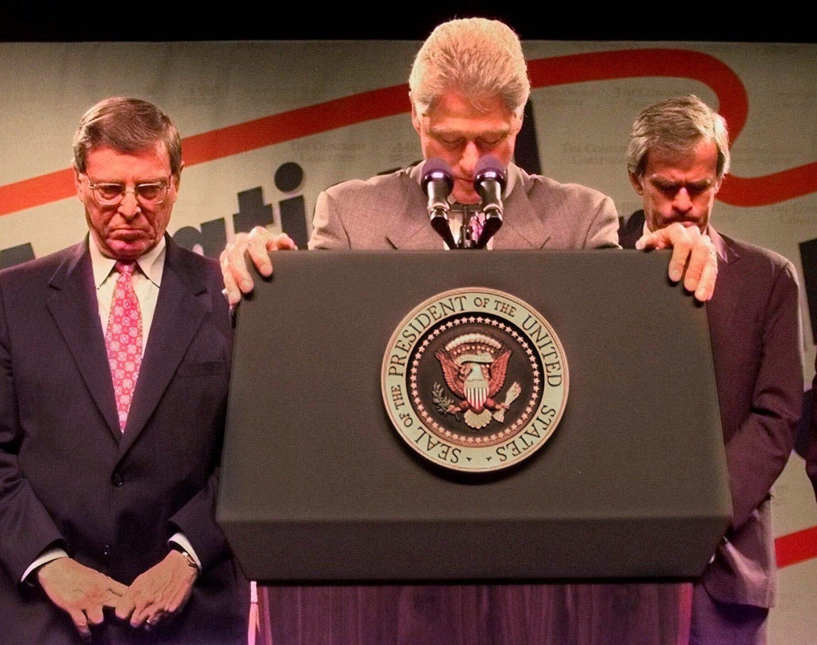 President Clinton, Sen. Pete Domenici, R-NM, left, and Sen. Jeff Bingaman, D-NM, right, bow their heads during a moment of silence in honor of the two policemen killed in the Capitol shooting before the start of the third national ``town hall'' on Social Security reform at the University of New Mexico Monday, July 27, 1998 in Albuquerque,  N.M.  (AP Photo/Greg Gibson)