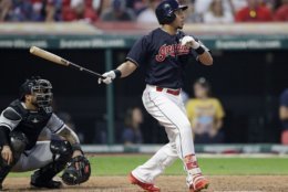 Cleveland Indians' Michael Brantley watches his ball after hitting a one-run double in the seventh inning of a baseball game against the Chicago White Sox, Tuesday, June 19, 2018, in Cleveland. Rajai Davis scored on the play. Catcher Omar Narvaez watches. (AP Photo/Tony Dejak)