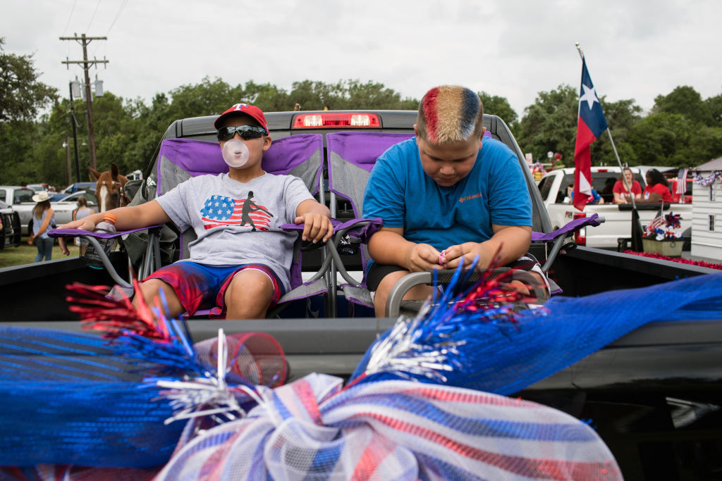 ROUND TOP, TX - JULY 04: (Left to right) Hunter Sabo, 11, and Ethan Tarnowski, 11, sit in the back of a pickup truck as they wait for the start of the 168th annual Round Top Fourth of July Parade on July 4, 2018 in Round Top, Texas. The Round Top community's Fourth of July celebration started in 1851 and is known as the longest running Fourth of July celebration west of the Mississippi. (Photo by Tamir Kalifa/Getty Images)