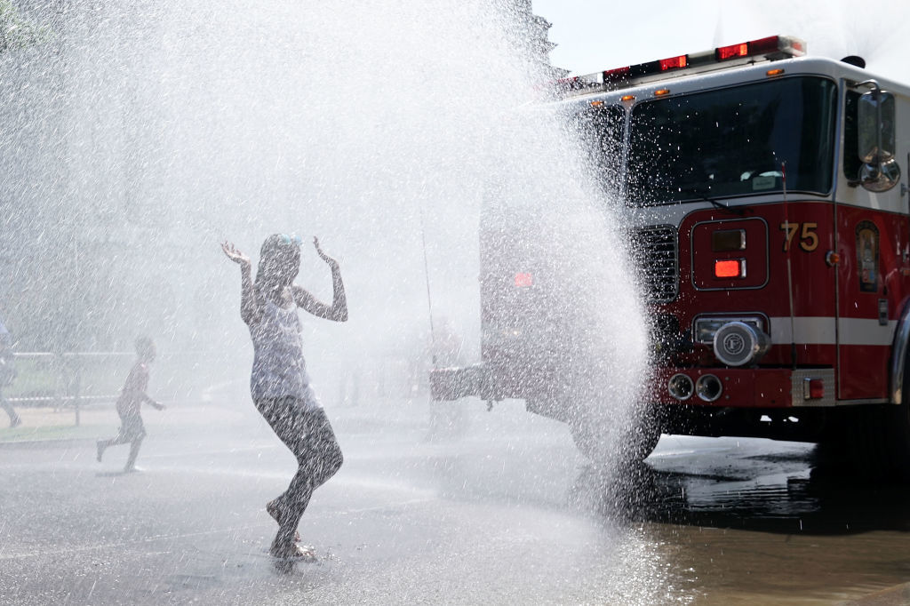 WASHINGTON, DC - JULY 04:  Children cool themselves in water spray from a fire truck outside the annual Smithsonian Folklife Festival on Independence Day July 4, 2018 in Washington, DC.  An oppressive heat has settled over much of the nation and  is expected to last at least through the end of the week, according to forecasts.  (Photo by Alex Wong/Getty Images)