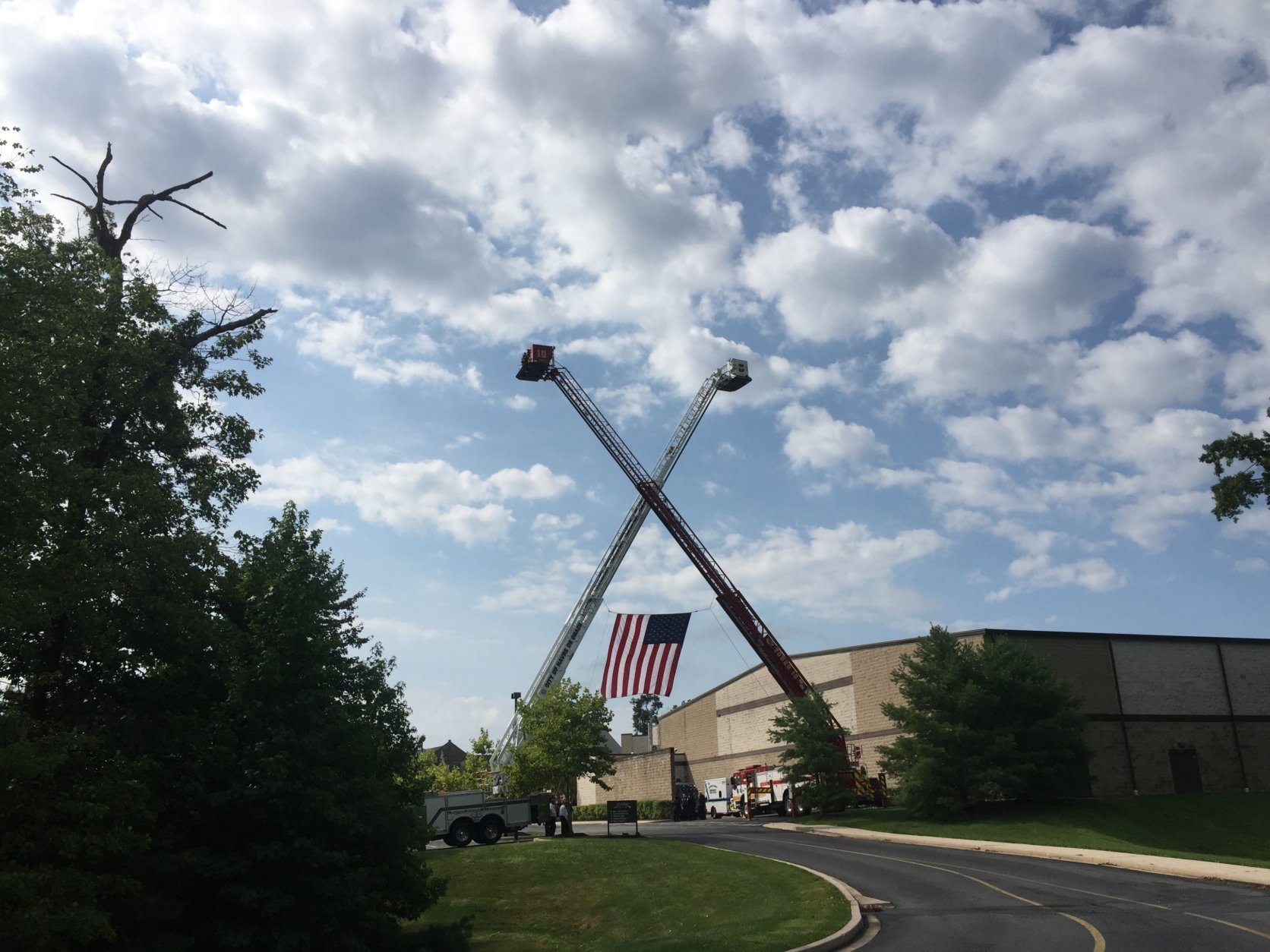 When Howard County Fire Engine 101 pulled into the parking lot of the Mountain Christian Church in Joppa, Maryland, it went under a large American flag held up by two ladder trucks. (WTOP/Mike Murillo)