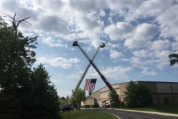 When Howard County Fire Engine 101 pulled into the parking lot of the Mountain Christian Church in Joppa, Maryland, it went under a large American flag held up by two ladder trucks. (WTOP/Mike Murillo)