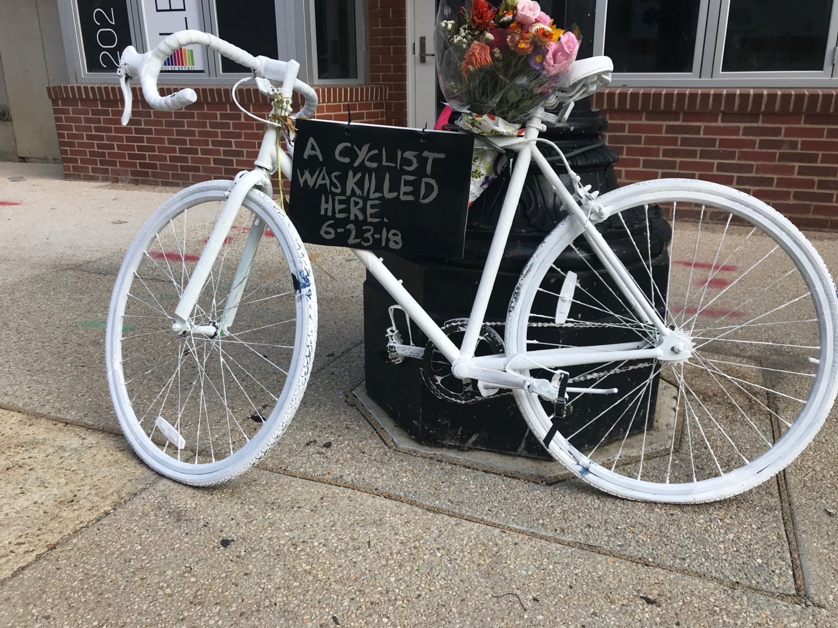 A so-called ghost bike painted white and decorated with a bouquet of flowers marks the spot where 19-year-old Malik Habib died. (WTOP/Dick Uliano)