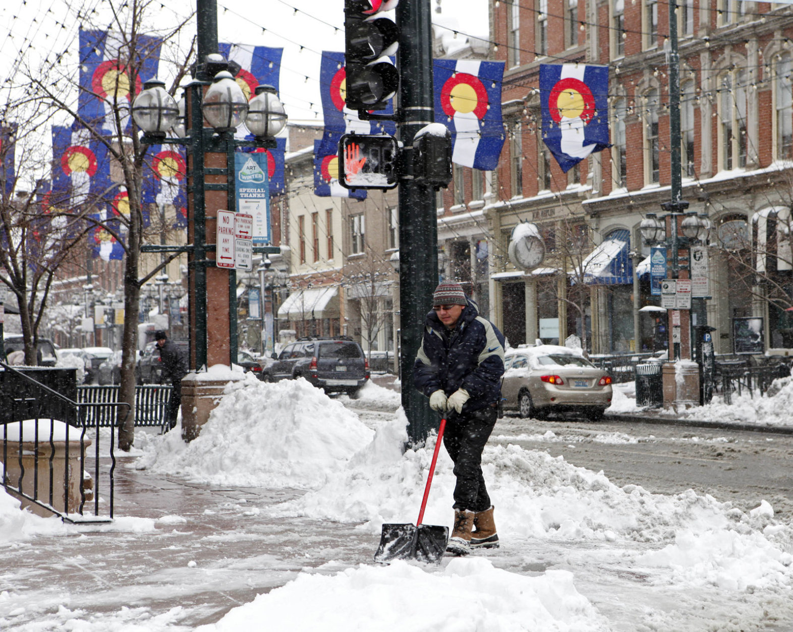 Workers clear the sidewalk on Larimer Square in downtown Denver on Friday, Feb. 3, 2012, after a snow storm hit Denver with 10 inches of snow overnight.   A powerful winter storm swept across Colorado on Friday as it headed east, bringing blizzard warnings to eastern Colorado and western Kansas, and winter storm warnings for southeast Wyoming and western Nebraska.  (AP Photo/Ed Andrieski)