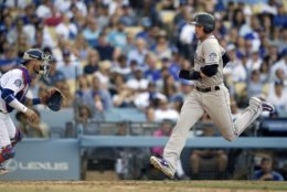 Colorado Rockies' Trevor Story, right, scores on single by Chris Iannetta as Los Angeles Dodgers catcher Yasmani Grandal looks for a throw during the seventh inning of a baseball game Saturday, June 30, 2018, in Los Angeles. (AP Photo/Mark J. Terrill)