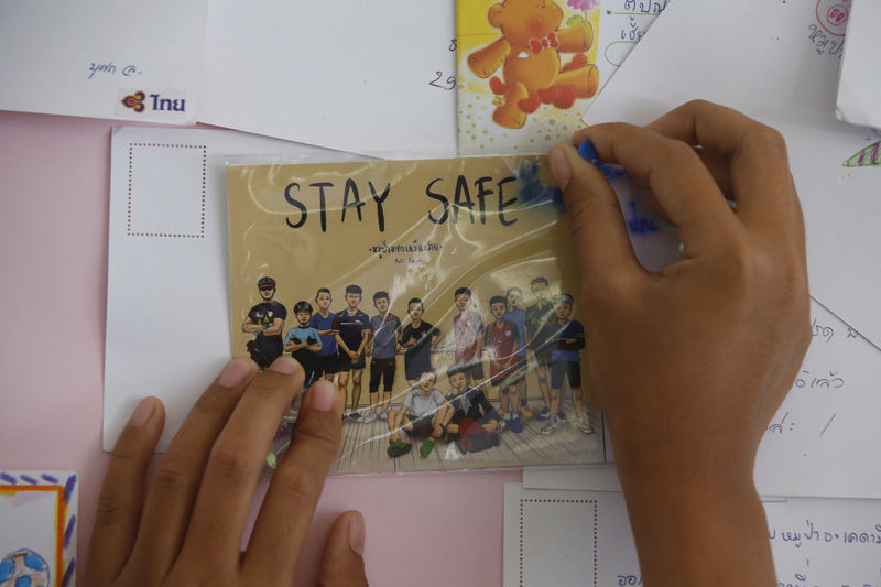 A Thai well wisher puts a poster to pray for boys and their soccer coach who have been trapped since June 23, in Mae Sai, Chiang Rai province, northern Thailand Monday, July 9, 2018. Expert divers Sunday rescued four of 12 boys from a flooded cave in northern Thailand, as a dangerous and complicated operation unfolded amid heavy rain and the threat of rising water underground. (AP Photo/Sakchai Lalit)