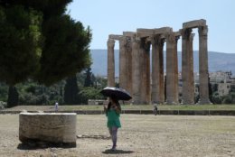 A tourist holds an umbrella to protect from the sun as she visits the Temple of Zeus in Athens, Tuesday, July 7, 2015. This is Greek tourism - July 2015 style - as the peak summer season in one of the worlds most popular destinations is glitched by a financial crisis of frightening proportions. The World Travel and Tourism Council said tourisms direct contribution to the Greek economy was more than 29 billion euros in 2014, accounting for just over 17 percent of the countrys GDP. (AP Photo/Spyros Tsakiris)
