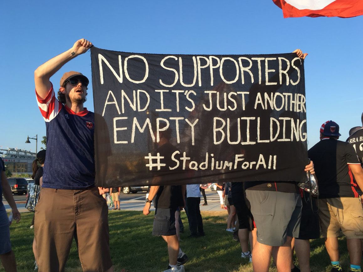 Protesters hold signs during D.C. United's first game at Audi Field on Saturday, July 14, 2018. (WTOP/Liz Anderson)