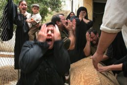 The family of a child, who relatives would only identify as a 9-year-old boy named Ahmed, wail over his coffin during his funeral at their home near the scene of suicide car bomb attack which killed him in Baghdad, Iraq Wednesday, July 13, 2005. A suicide car bomber sped to American soldiers as they distributed candy to children and detonated his vehicle Wednesday, killing up to 27 other people, U.S. and Iraqi officials said. One U.S. soldier and about a dozen children were among the dead. (AP Photo/Hadi Mizban)