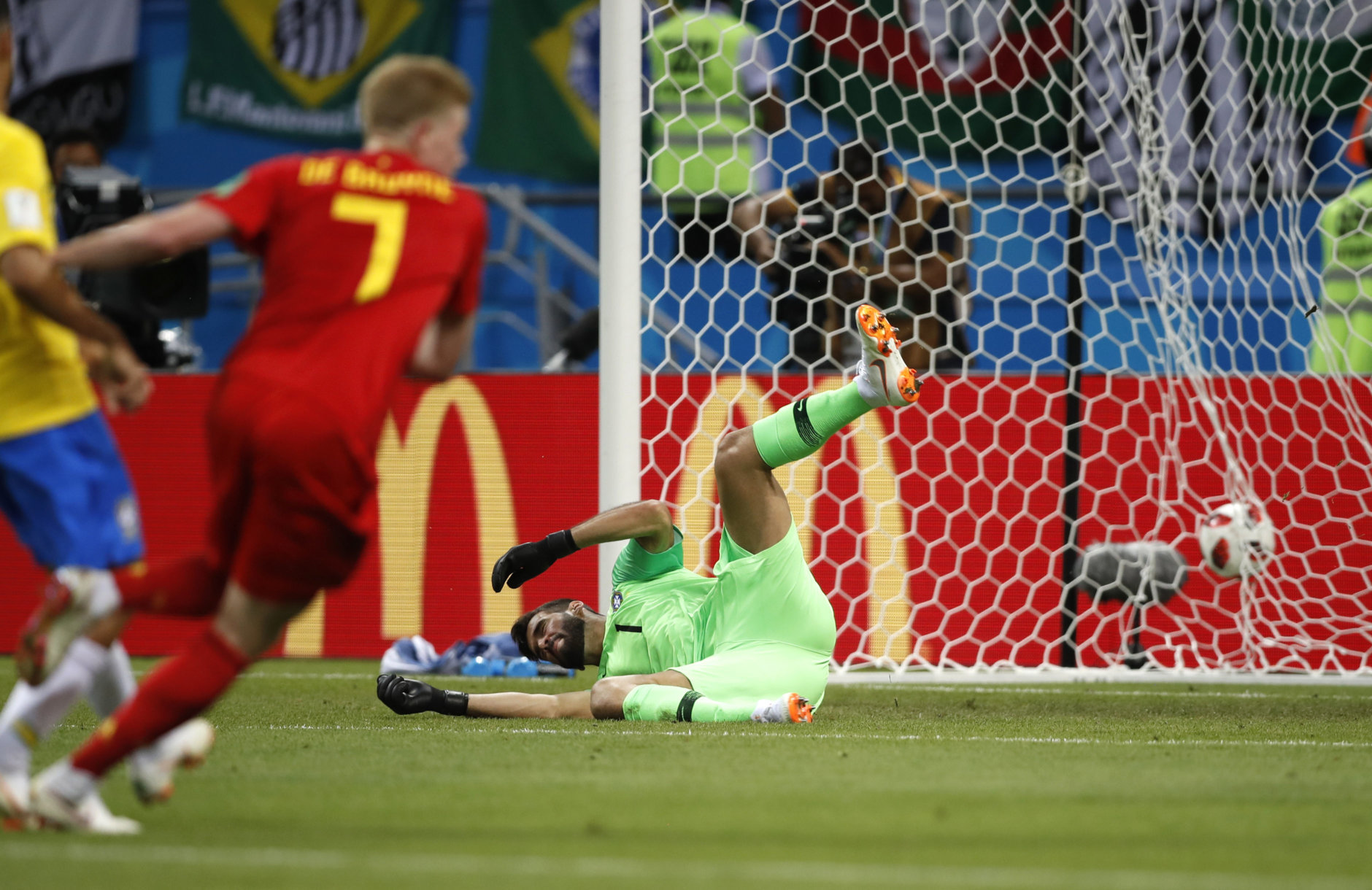 Brazil goalkeeper Alisson sits on the pitch after Belgium's Kevin De Bruyne, left, scored his side's second goal during the quarterfinal match between Brazil and Belgium at the 2018 soccer World Cup in the Kazan Arena, in Kazan, Russia, Friday, July 6, 2018. (AP Photo/Francisco Seco)
