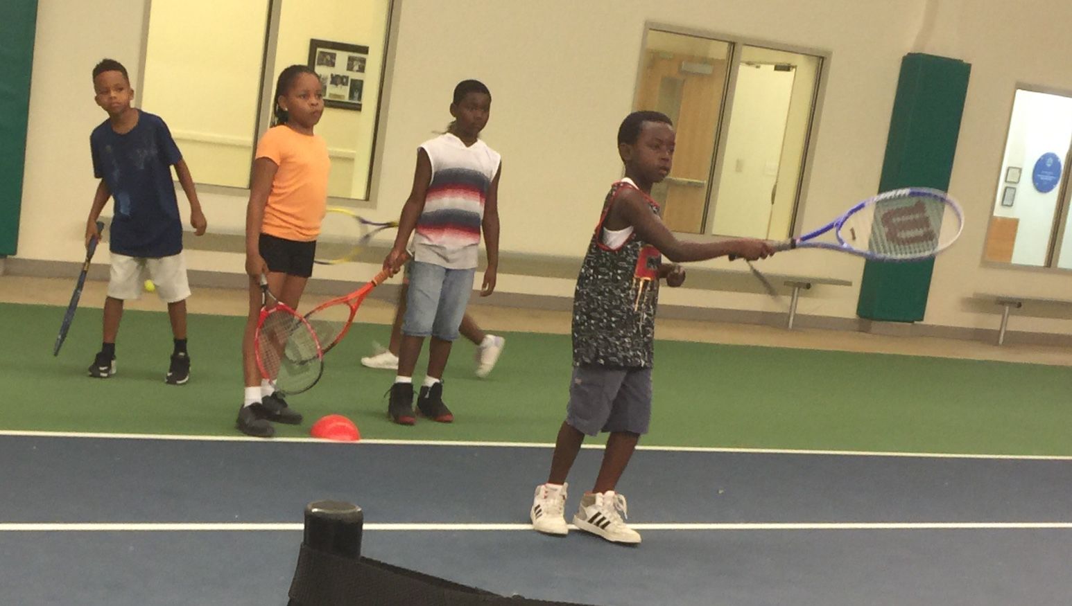 Children take turns hitting balls tossed to them by a teen aged employee of WTEF. (WTOP/Kristi King)