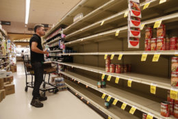 A worker looks at empty shelves for canned goods at a supermarket ahead of Hurricane Lane, Friday, Aug. 24, 2018, in Honolulu. (AP Photo/John Locher)
