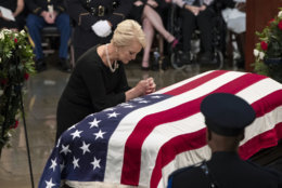 Cindy McCain, wife of Sen. John McCain, R-Ariz., leans over his flag-draped casket in the U.S. Capitol rotunda during a farewell ceremony, Friday, Aug. 31, 2018, in Washington. The six-term Republican senator, who lived and worked in the nation's capital over four decades, is lying in state under the U.S. Capitol rotunda for a ceremony and public visitation.  (AP Photo/J. Scott Applewhite)